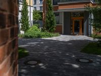 a residential driveway with a bench and bushes in between buildings and green grass on either side