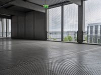 large open building with a metal mesh floor covering the floor and ceiling, looking out onto large cityscape outside