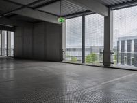 large open building with a metal mesh floor covering the floor and ceiling, looking out onto large cityscape outside