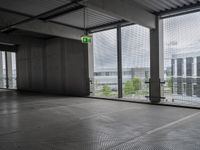 large open building with a metal mesh floor covering the floor and ceiling, looking out onto large cityscape outside