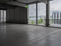 large open building with a metal mesh floor covering the floor and ceiling, looking out onto large cityscape outside