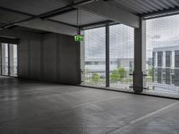 large open building with a metal mesh floor covering the floor and ceiling, looking out onto large cityscape outside