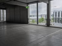 large open building with a metal mesh floor covering the floor and ceiling, looking out onto large cityscape outside