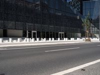 the empty street near the building is lined with white pillars and fenced streets in front