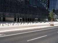 the empty street near the building is lined with white pillars and fenced streets in front