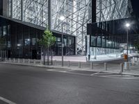 a very pretty building with a big glass front by some light poles on a city street