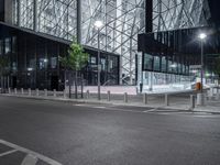 a very pretty building with a big glass front by some light poles on a city street