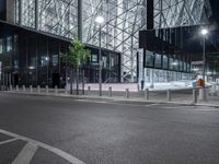 a very pretty building with a big glass front by some light poles on a city street