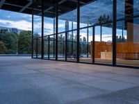 a building with glass walls and a large bench in the back room surrounded by trees