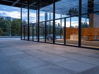 a building with glass walls and a large bench in the back room surrounded by trees