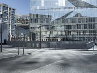 a building with glass and a sky background at the corner of the street in front of it is a traffic light and some windows