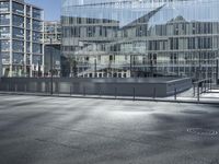 a building with glass and a sky background at the corner of the street in front of it is a traffic light and some windows