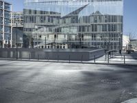 a building with glass and a sky background at the corner of the street in front of it is a traffic light and some windows