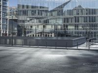 a building with glass and a sky background at the corner of the street in front of it is a traffic light and some windows