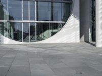 a woman with a black backpack is walking in front of a glass - fronted building