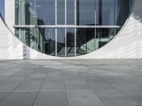 a woman with a black backpack is walking in front of a glass - fronted building