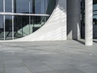 a woman with a black backpack is walking in front of a glass - fronted building