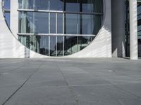 a woman with a black backpack is walking in front of a glass - fronted building