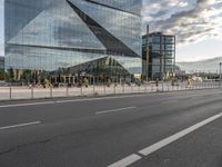 there is a bench along with a large building on it, reflecting in the glass windows