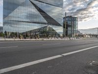 there is a bench along with a large building on it, reflecting in the glass windows