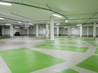 an indoor parking lot with green and white flooring and a payphone in the middle of the photo