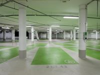 an indoor parking lot with green and white flooring and a payphone in the middle of the photo