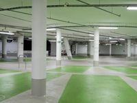 an indoor parking lot with green and white flooring and a payphone in the middle of the photo