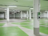 an indoor parking lot with green and white flooring and a payphone in the middle of the photo