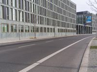 there is an empty street next to buildings and a building with large windows on each side