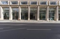 a street view of a tall glass building with no parking space for cars to walk by