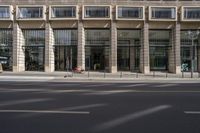 a street view of a tall glass building with no parking space for cars to walk by