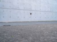 an open fire hydrant in front of a large white wall with crosses on it