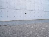 an open fire hydrant in front of a large white wall with crosses on it