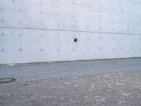 an open fire hydrant in front of a large white wall with crosses on it