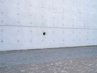 an open fire hydrant in front of a large white wall with crosses on it