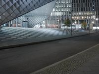 a big building with many windows sitting in the dark and there is a street going by