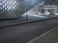 a big building with many windows sitting in the dark and there is a street going by