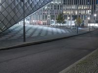 a big building with many windows sitting in the dark and there is a street going by