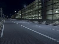 an empty street near an office building at night as seen on the streets side of the road