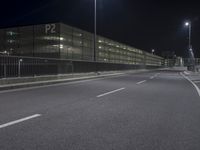 an empty street near an office building at night as seen on the streets side of the road