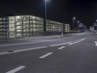 an empty street near an office building at night as seen on the streets side of the road