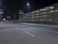 an empty street near an office building at night as seen on the streets side of the road