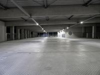 a large parking garage filled with lots of cement walls and floors at night, which is empty