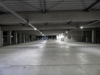 a large parking garage filled with lots of cement walls and floors at night, which is empty