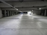 a large parking garage filled with lots of cement walls and floors at night, which is empty