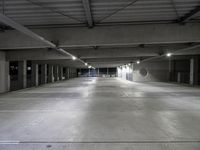 a large parking garage filled with lots of cement walls and floors at night, which is empty