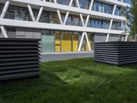 a sculpture sitting in the grass near an office building with multiple angles to each other