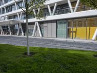 a sculpture sitting in the grass near an office building with multiple angles to each other