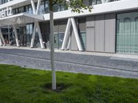 a sculpture sitting in the grass near an office building with multiple angles to each other