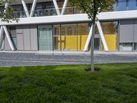 a sculpture sitting in the grass near an office building with multiple angles to each other